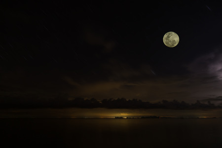 Full moon in the dark sky with rain clouds and soft light the motion star at the lake.