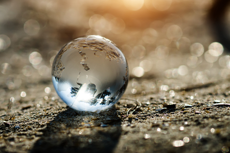 Maple glass with world map lay on the sand and sunlightの写真素材