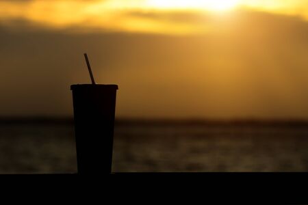 Black silhouette of paper glass with sunset at lakeの写真素材