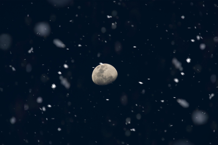 The moon in the dark blue night with snow falling.の写真素材