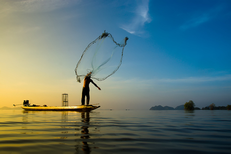 fisherman are throwing fishing nets during sunrise sky, Thailand.の写真素材