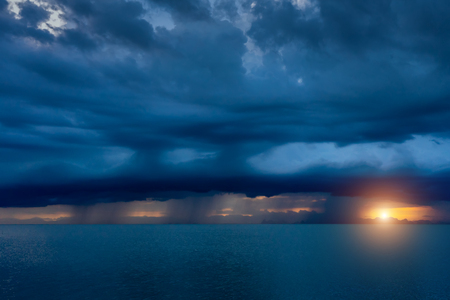 Seascape with rain cloud in blue color and small sunlight.の写真素材