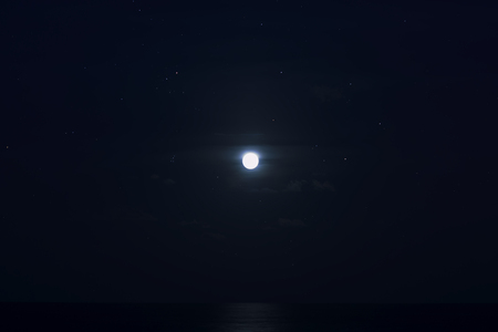 The full moon in the dark blue night with stars above the sea.
