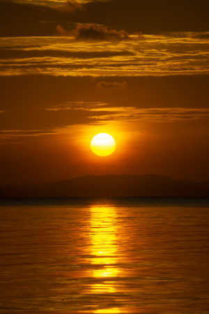 Vertical image of Sunset at the lake with silhouette mountain on golden hour.の写真素材