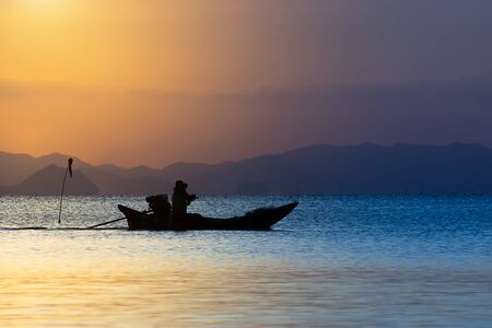 silhouette of the fishing boat on the lake with sunlight.の写真素材