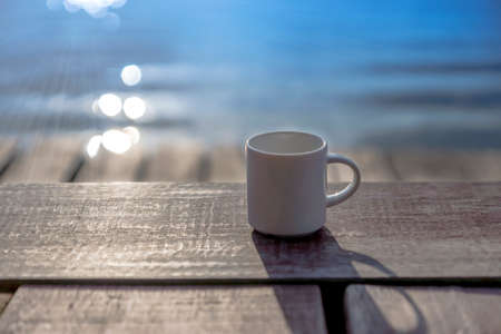 White coffee mug on wooden with blur background in the morning.