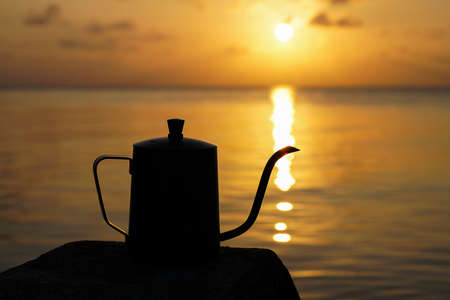 silhouette of a coffee kettle at the lake with sunlight.の写真素材