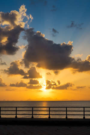 Seascape, The sun behind clouds on sunset sky at the lake with silhouette fence.の写真素材