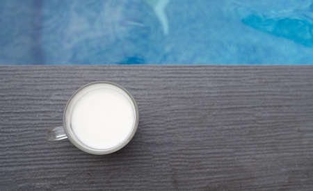 A cup of hot latte coffee is beside the pool in the house.の写真素材