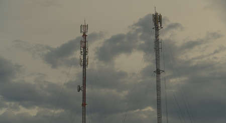 Two towers with antennas and a device for providing communication to move on the background of the sky at dusk.の写真素材