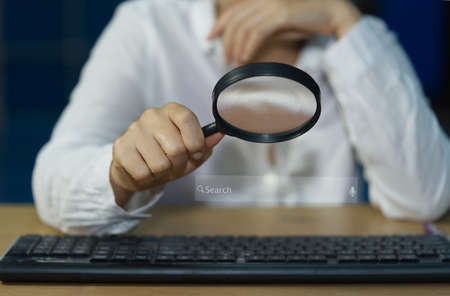 Search Technology SEO Search Engine Optimization Woman's hand using a magnifying glass and laptop keyboard to find what interests them. Find information with your website. internet network.の写真素材