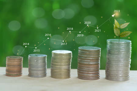Stack of coins isolated from white background with graph lines reporting corporate earnings growth...