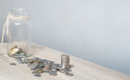 A stack of coins on a table with a glass float indicates savings ideas, daily spending planning, including goals for saving money for retirement, white background with copy space.の写真素材