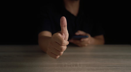 customer service performance analysis Man's hand using smartphone with company successful male index finger sign Portrait of a man on the table pointing up yes ok thumbs up in customer service networkの写真素材