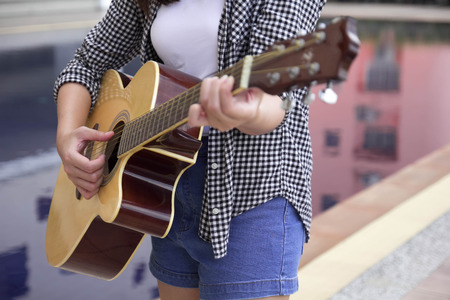 Close-up Asian Woman playing guitar instrument by the poolAsian Woman playing flute instrument in Silhouette shape with blue sky in backgroundの写真素材