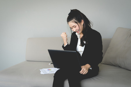 Excited happy young woman with fists up, Air punch.
Business girl  in black suit punching in the air.
victory and success concept.の写真素材