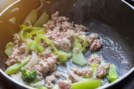 Cooking pork chop with green chili and Broccoli in black hot pan with smoke, Thai traditional food in kitchen concept.の写真素材