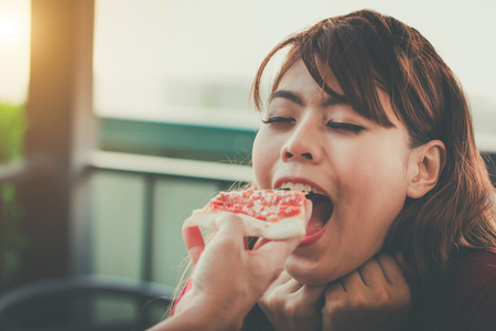 Close up boyfriend hand feeding piece of pizza to girlfriend mouth. Young woman enjoy eating italian food. female feeling happy from a man.の写真素材