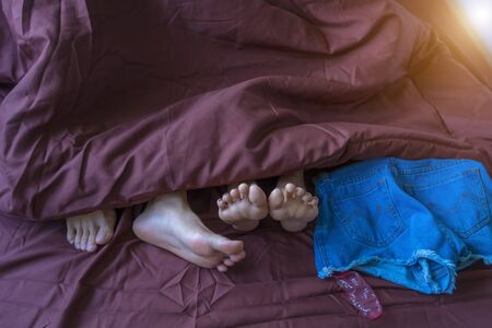 Close up couple feet lying in bed. Male and female feet on bed - Loving couple having sex under...