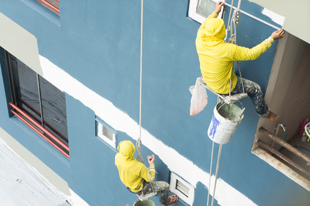painters hanging on roll, painting color on building wall.
Young painting facade builder worker with roller brush, working on high building, working together concept.
safety construction with lift ropt belt in city.の写真素材