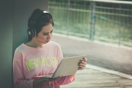 Young Business woman working with laptop feeling tired. fashion girl with headphones. Asian Female listening bad news from earphones.の写真素材