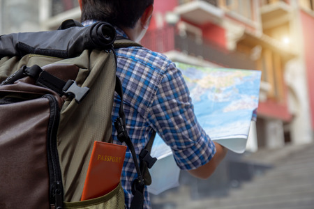 Young man looking in open map. Traveler standing with road map in hands.
Hipster backpacker lost in the city, holding city guide, looking excited on adventure, smiling while reading map.の写真素材