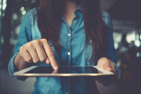 Casual business woman using tablet pc.
Female hands working with tablet touching screen computer. Woman using social network, working typing on technology device.の写真素材