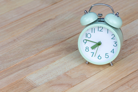 Close up green Alarm clock placed on wooden table floor. Background abstract image, beginning of the...