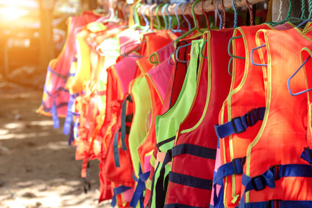 Life jacket orange color hanging on row. Life jackets, safety equipment prevent drowning. life security tool in water.の写真素材