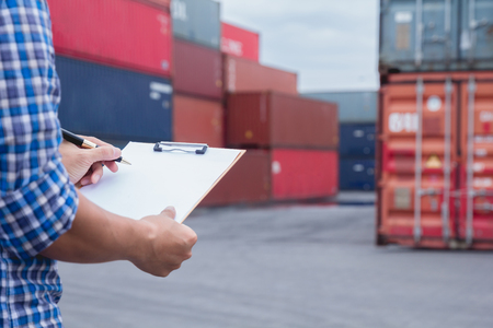 Man taking note checking cargo shipping at container yard area.
Worker man signing papers about import - export logistic business.の写真素材
