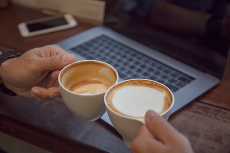 Business man holding coffee cup cheers over laptop computer. Business technology success concept.の写真素材