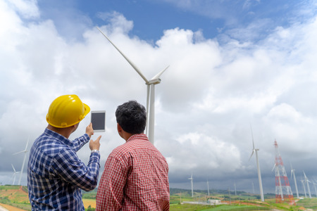 architecture businessman talking with partner about wind turbine farm project on tablet, technology...