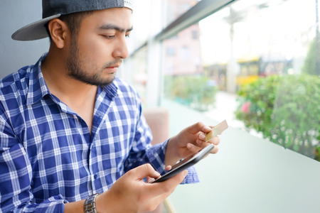 Man using mobile smartphone and credit card for online shopping in coffee shop.Casual businessman...