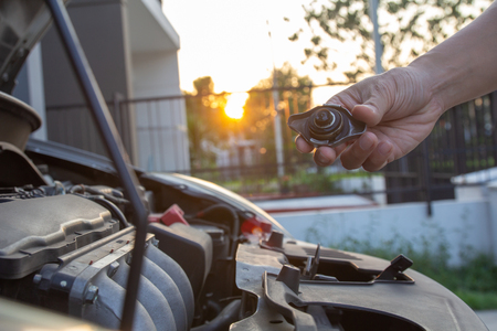 Mechanic man checking car engine radiator cooling tank water level.
Hand holding cap of radiator coolant car engine.
Car boiling water overheating problem, radiator fluid Service and maintenance vehicle car care concept.の写真素材