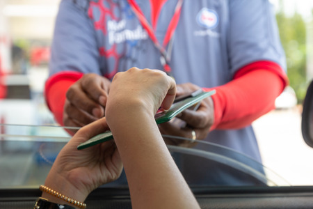 Woman in car paying gasoline with credit card, female holding debit card payment at gas station....