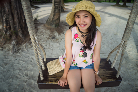 Asian girl with straw hat smiling and having fun on holiday.
Young woman lifestyle swinging sitting on swing hangs on coconut palm trees.
Traveler enjoying summer on tropical beach, paradise Island.の写真素材
