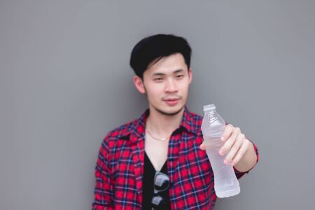 Young Asian male holding pure water bottle clean fresh diet drinking for healthy, fill energy after exercise playing sport workout on gray studio background
Close up thirsty man showing plastic water bottle.の写真素材