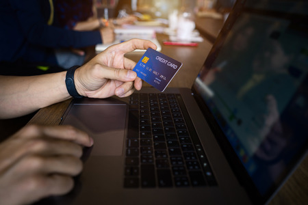 Man using credit card payment shopping online in public cafe. Internet data fraud risk.
Close up hand holding credit card typing ccv data on laptop computer.の写真素材