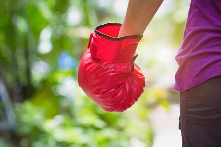 Woman wearing red boxer grove standing against green nature bokeh outdoor back view with copy space. business fighting victory concept.の写真素材
