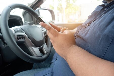 Man driver using mobile phone when driving car on road. people hand holding smart phone driving car,...
