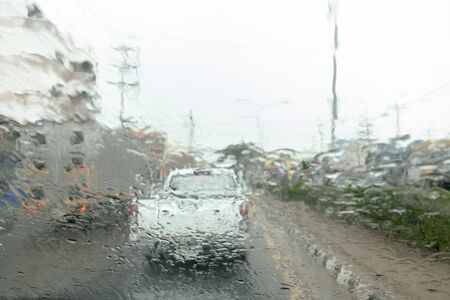 Blurry rain drop on window front car on the road. storm rain dangerous for driving car.の写真素材