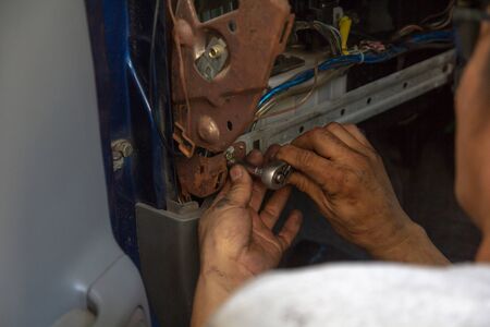 close up hands mechanic fixing car with wrench in garage.repair man working on car in service shop.の写真素材