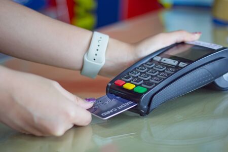 Young woman paying by credit card.Close up Female customer hands holding credit card and pay on...