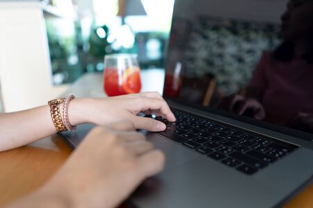Young business woman hands typing on laptop computer keyboard with fresh drinking on table.
Female working on notebook computer in cafe and drinking red juice.の写真素材