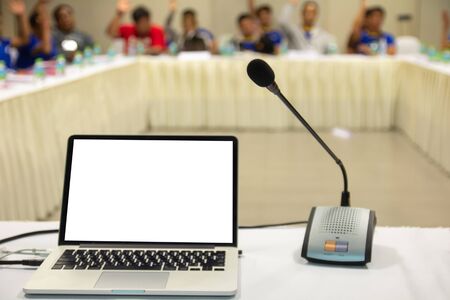 Mock up laptop computer with blank screen on table in meeting room with blur people hands up voting board in background.
Close up microphone on desk in conference seminar room.の写真素材