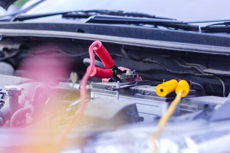 Charging dead battery car with electricity trough jumper cables line in garage service.の写真素材