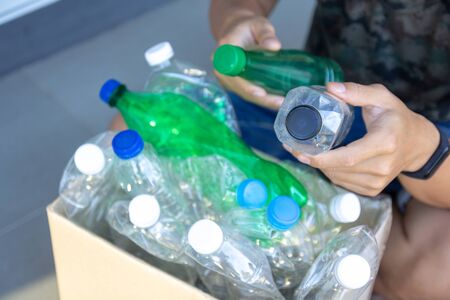 Hand  holding clear and green recyclable plastic bottle putting in paper garbage bin for recycling.
waste management and plastic reuse toÂ environmental protection world concept.の写真素材