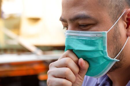 Asian man wearing protective face masks coughing. Sick man with flu wearing mask and blowing nose, epidemic flu concept.の写真素材