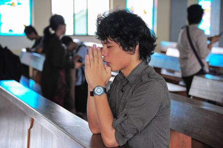 Closeup of a young man praying in christian churchのeditorial素材