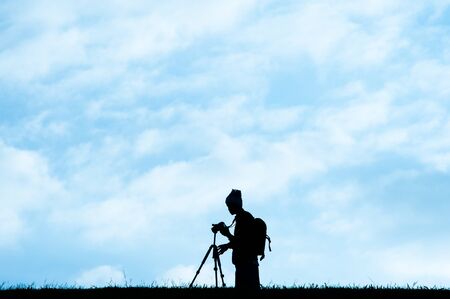 Silhouette of photographer over the sky